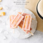 Stack of mango guava popsicles on top of plate of ice next to straw hat
