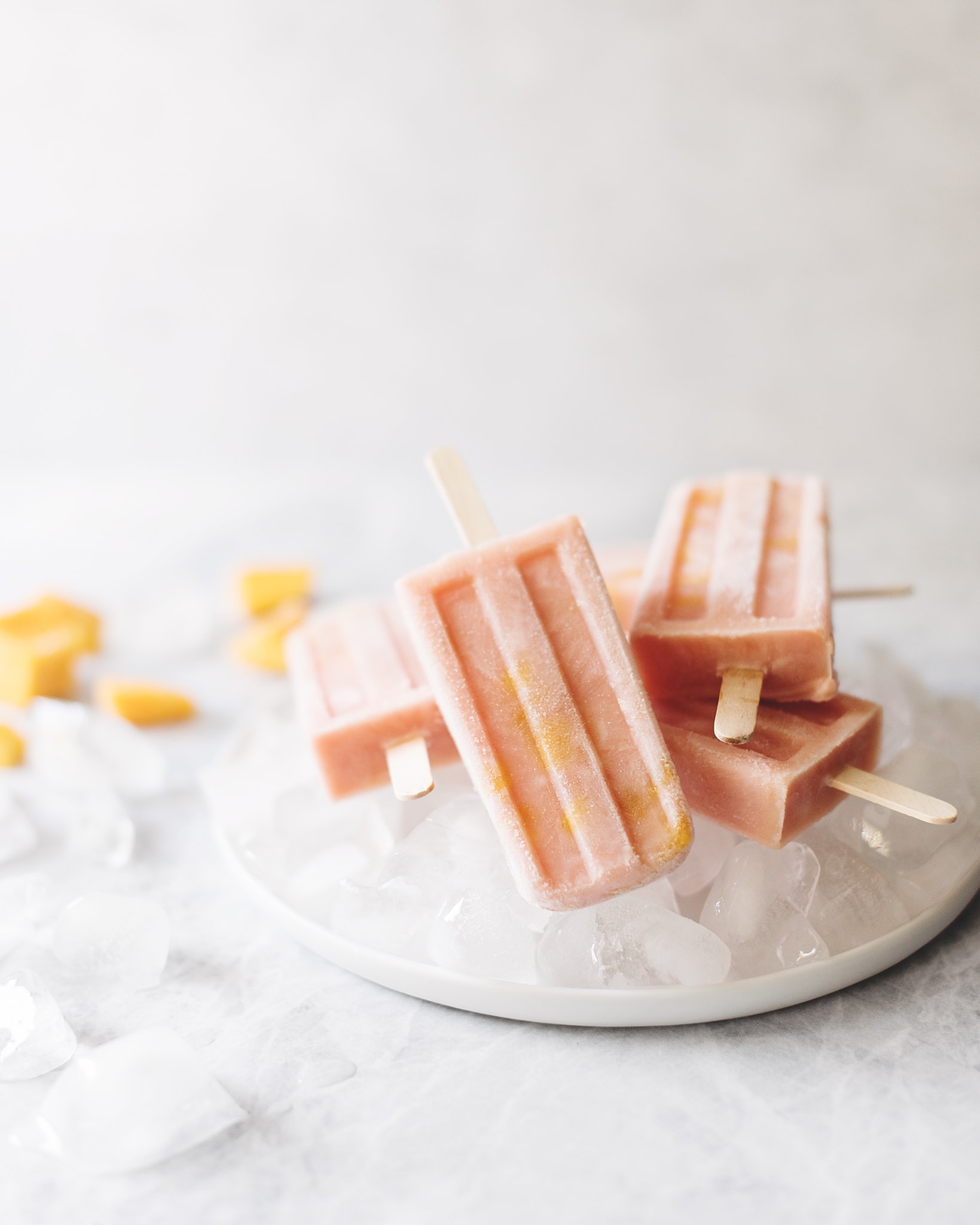 Stack of mango guava popsicles on top of plate of ice