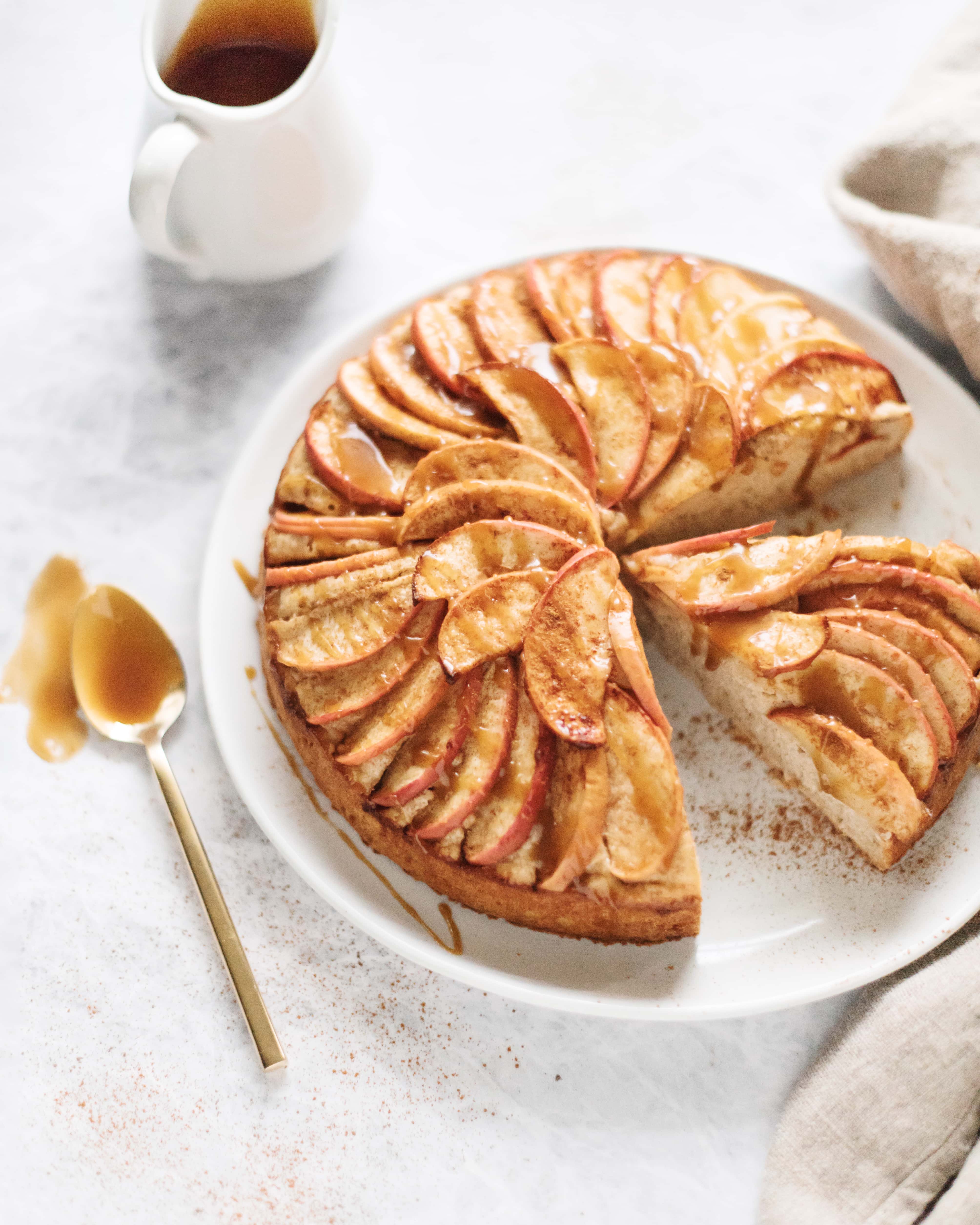 A slice cut out of a spiced apple cake with salted maple caramel drizzle