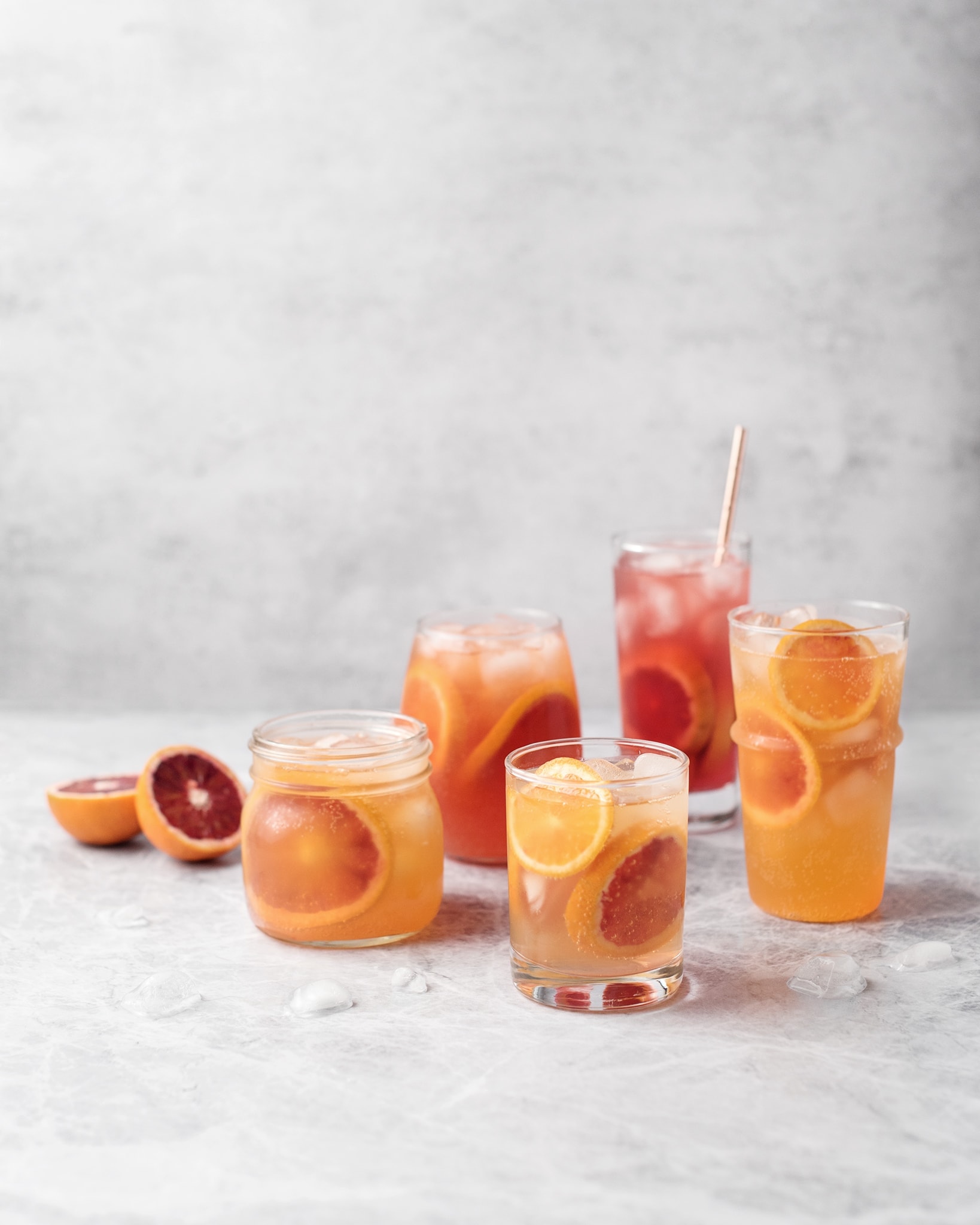 Glasses of blood orange paloma cocktails on grey background