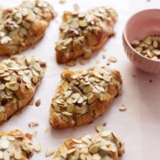 Almond croissants sprinkled with sliced almonds on pink background