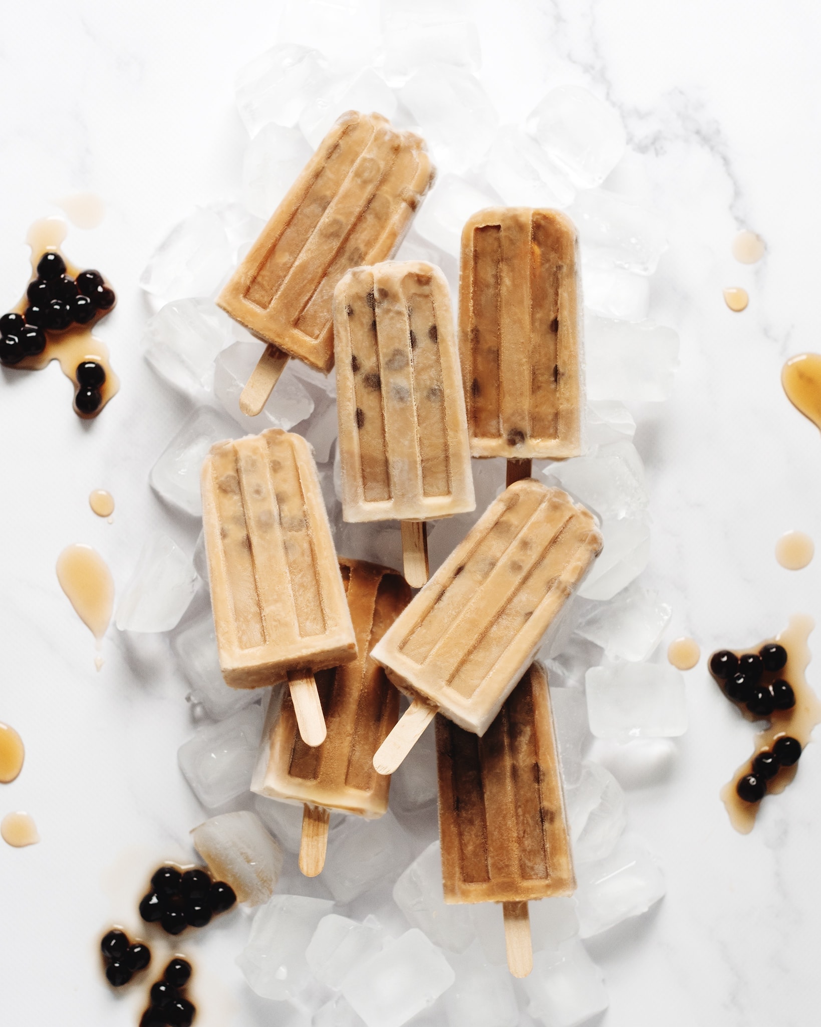 Several boba milk tea popsicles on top of ice cubes