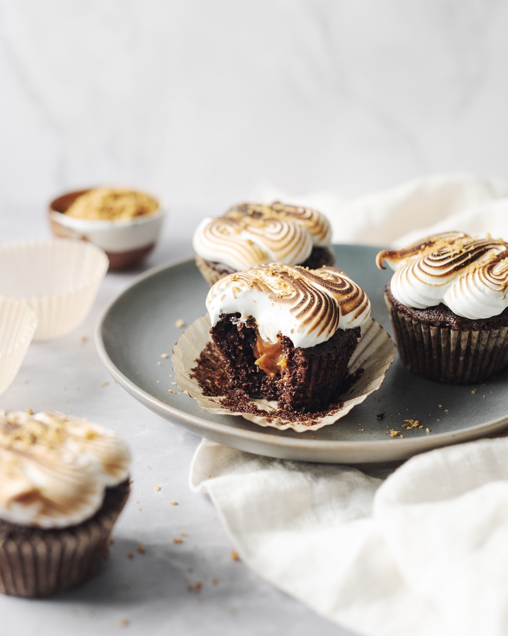 S'mores cupcakes with a bite taken out of one to reveal the caramel filling inside