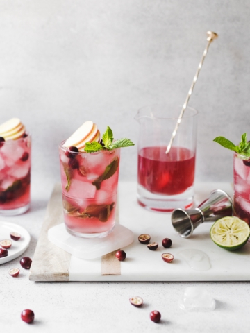 Cranberry apple mojitos on a marble and wood serving tray