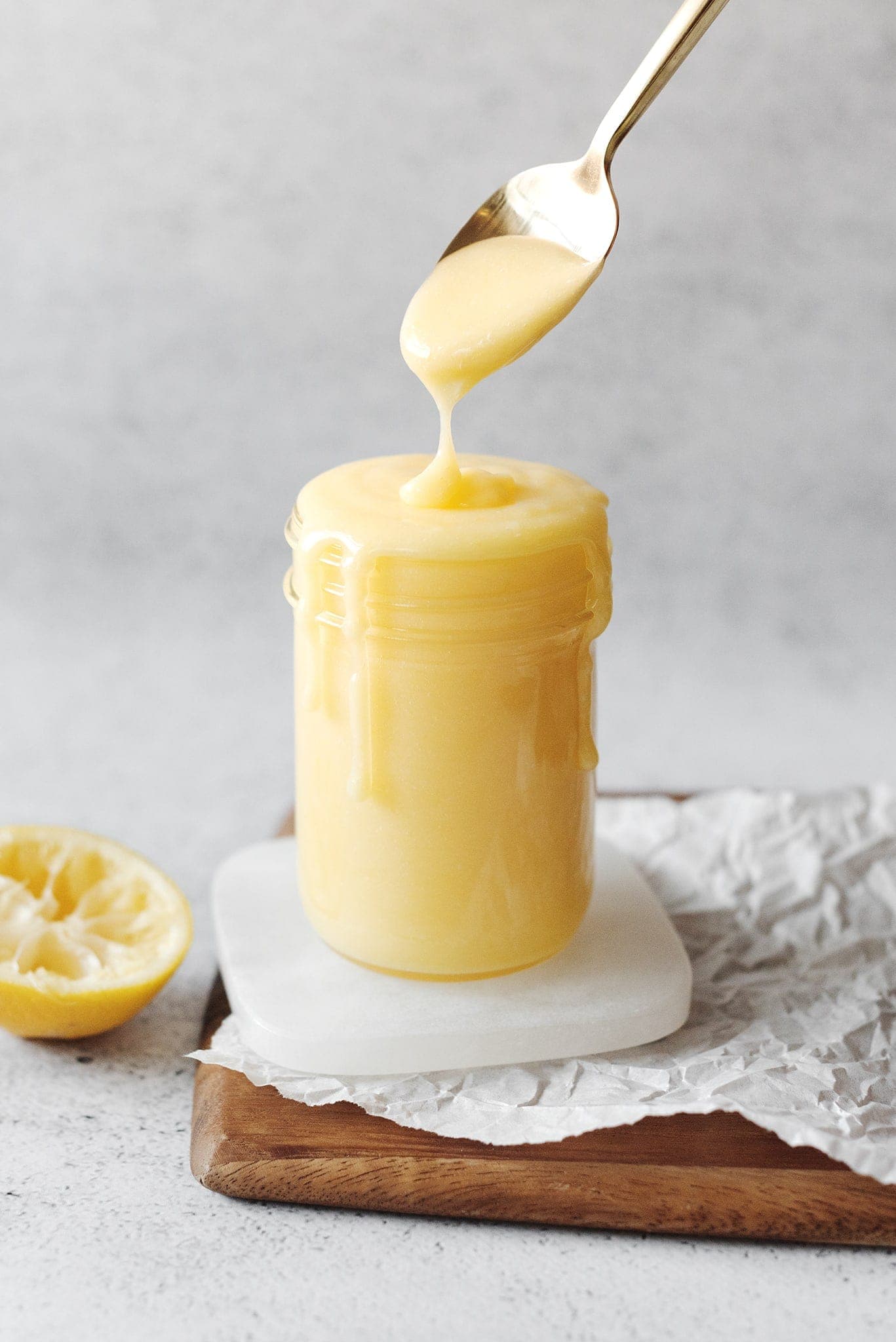 Lemon curd dripping from spoon into jar