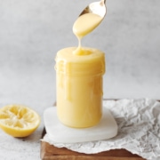 Lemon curd dripping from spoon into jar