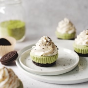 Matcha cheesecakes topped with whipped cream on plate with oreos
