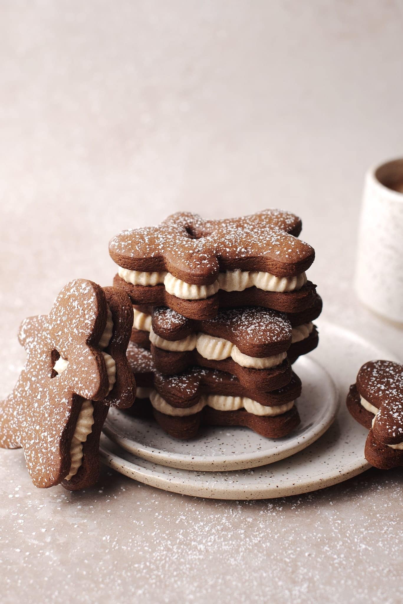 Stack of gingerbread sandwich cookies with ginger cream filling on plate