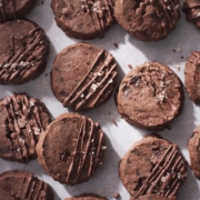 Many chocolate sablé cookies on scattered on baking sheet