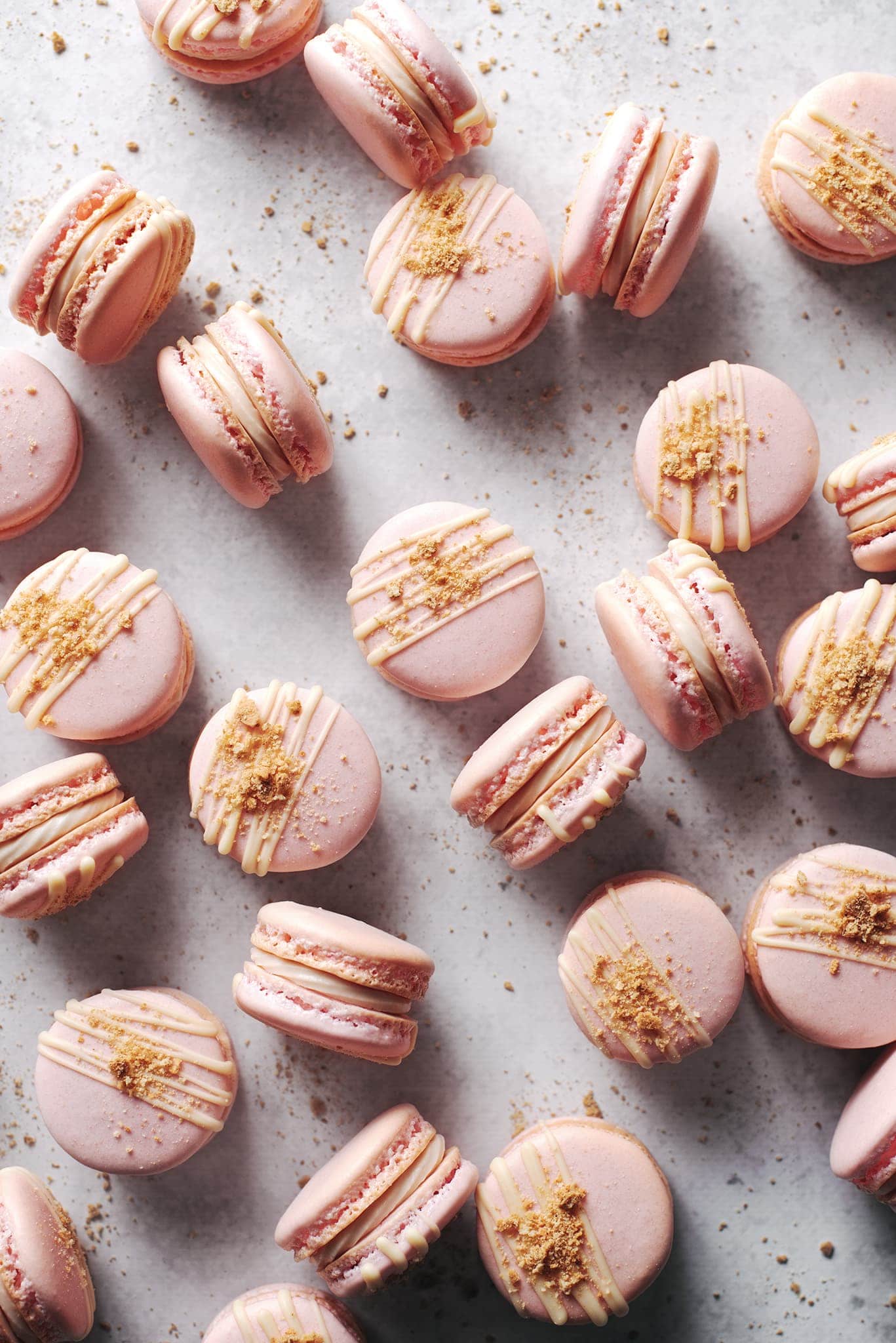 pink strawberry cheesecake macarons scattered on grey surface