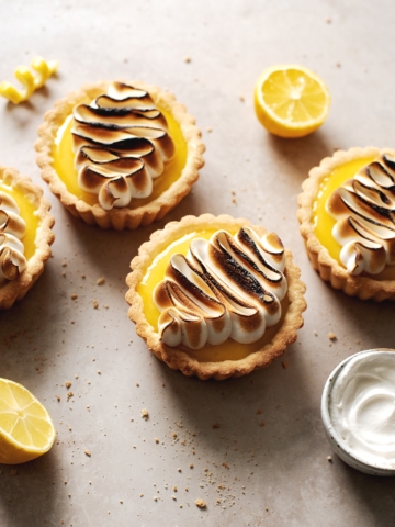 Piped squiggle design of toasted meringue on top of lemon tarts