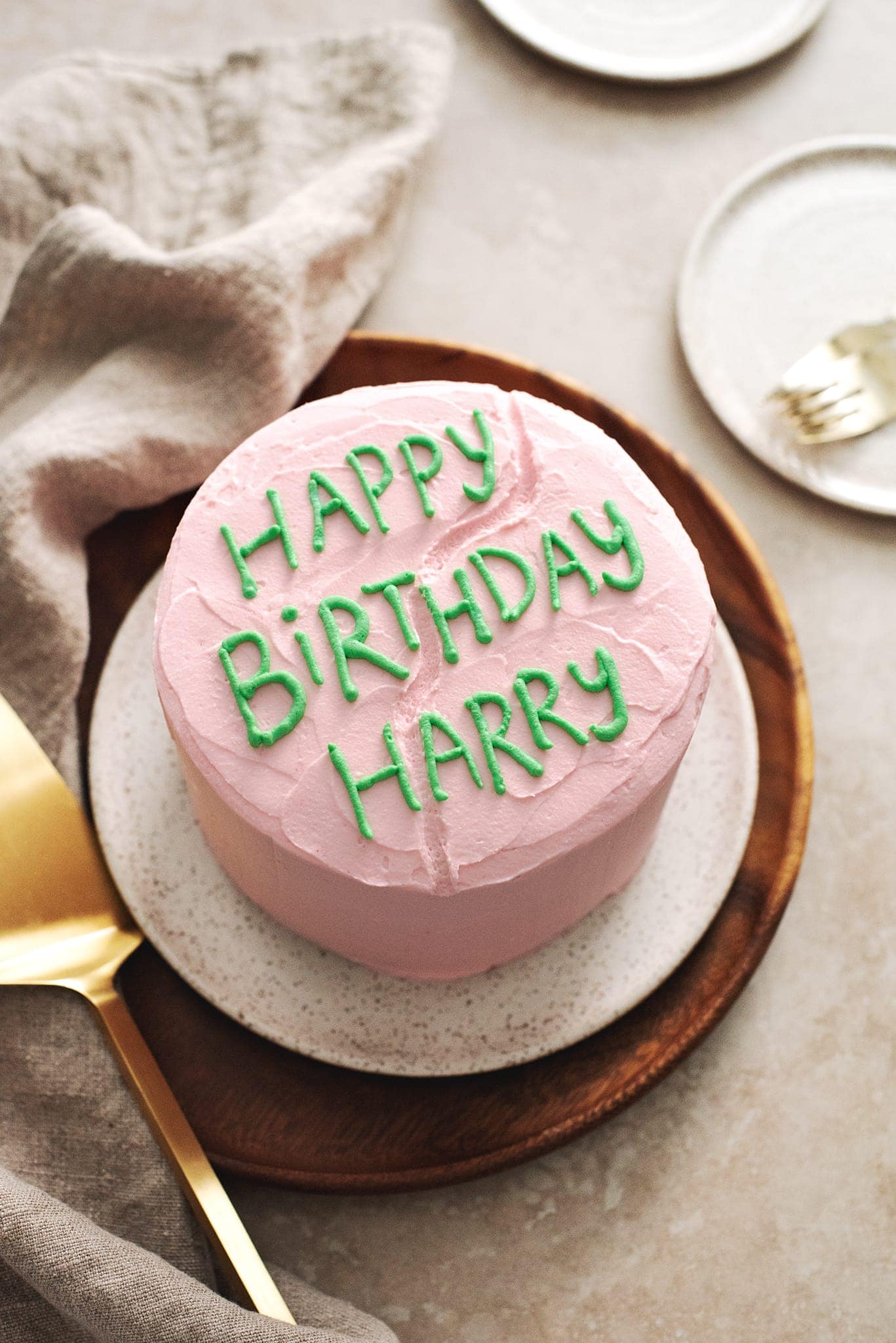 Pink cake with ‘Happy Birthday Harry’ written in green icing