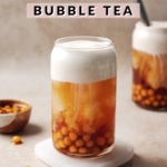 Glass of sweet potato bubble tea with sweet potato boba pearls and a layer of sweet cream dripping into black tea