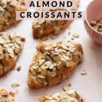 Almond croissants sprinkled with sliced almonds on pink background