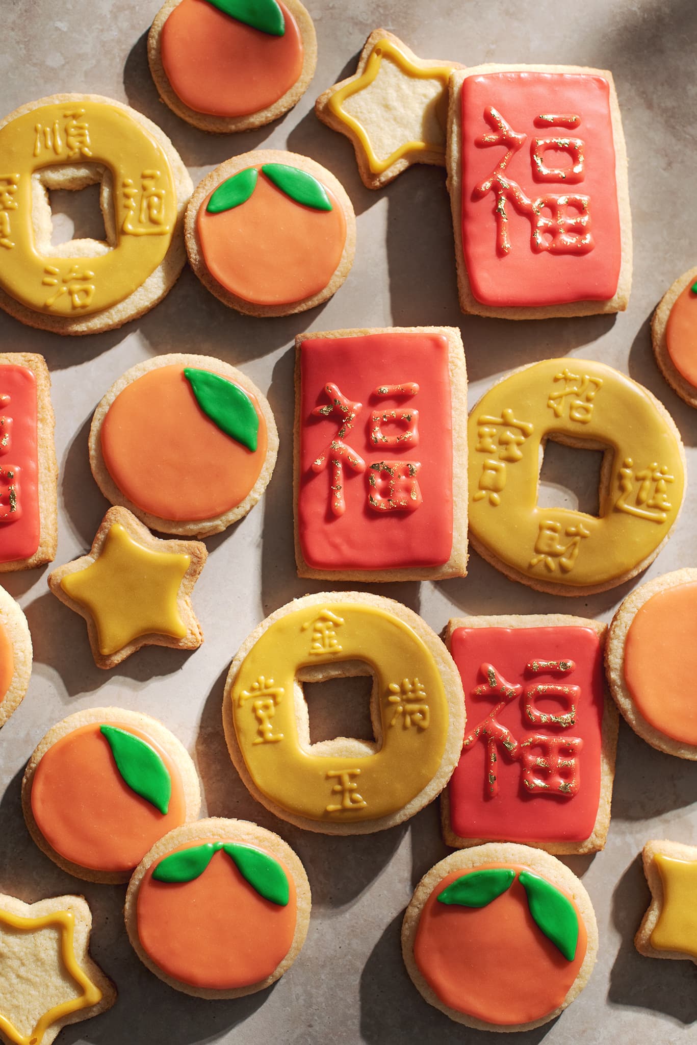 chinese new year cookies decorated as red envelopes, mandarin oranges, and coins