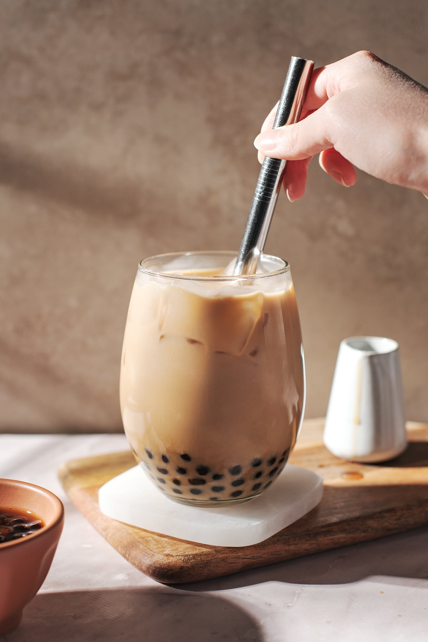 stirring a glass of earl grey bubble tea with a straw