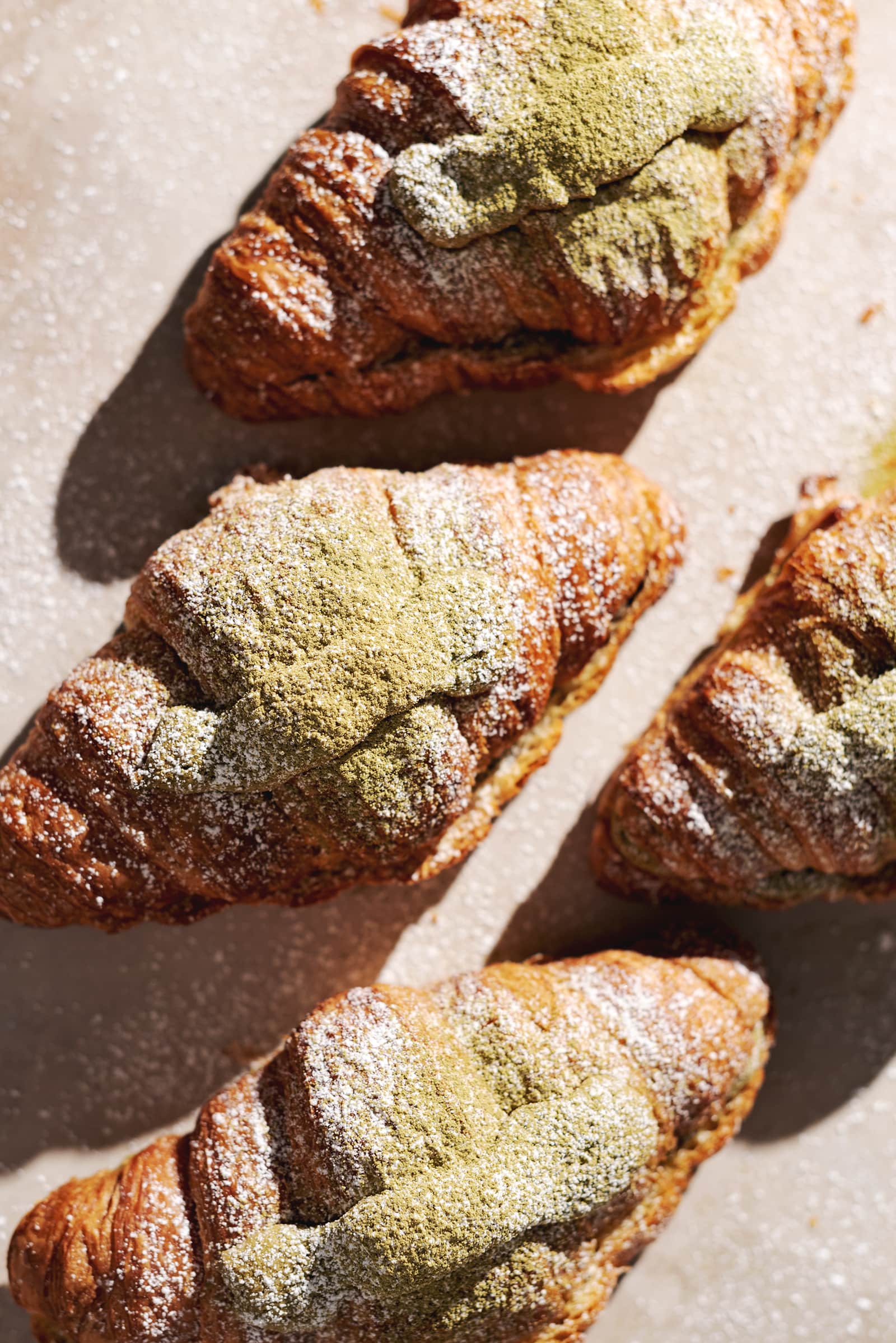 matcha almond croissants dusted with powdered sugar and matcha powder