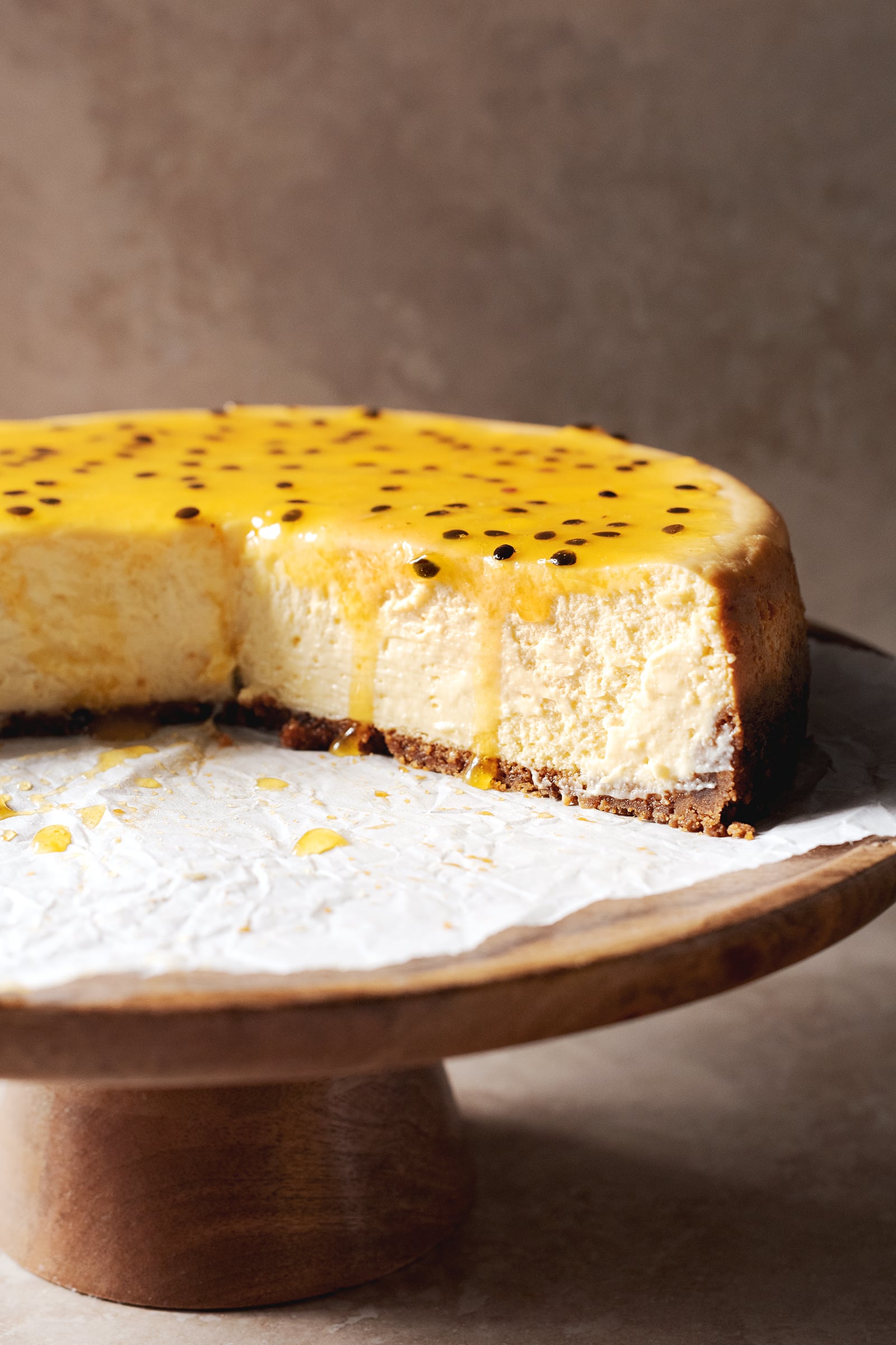 Cross section of a cheesecake with passionfruit puree dripping down the front.