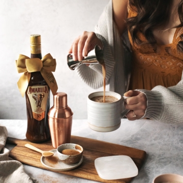 Pouring Amarula cream liqueur into a mug of hot chocolate and coffee