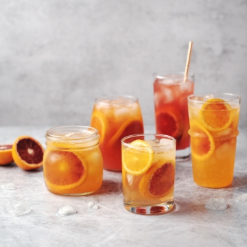 Glasses of blood orange paloma cocktails on grey background