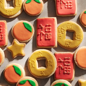 chinese new year cookies decorated as red envelopes, mandarin oranges, and coins