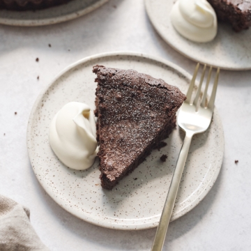 A slice of flourless chocolate cake on a plate with whipped cream