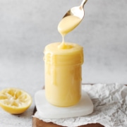 Spoon dripping lemon curd into glass jar