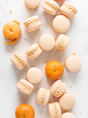 Mandarin orange macarons scattered on marble counter