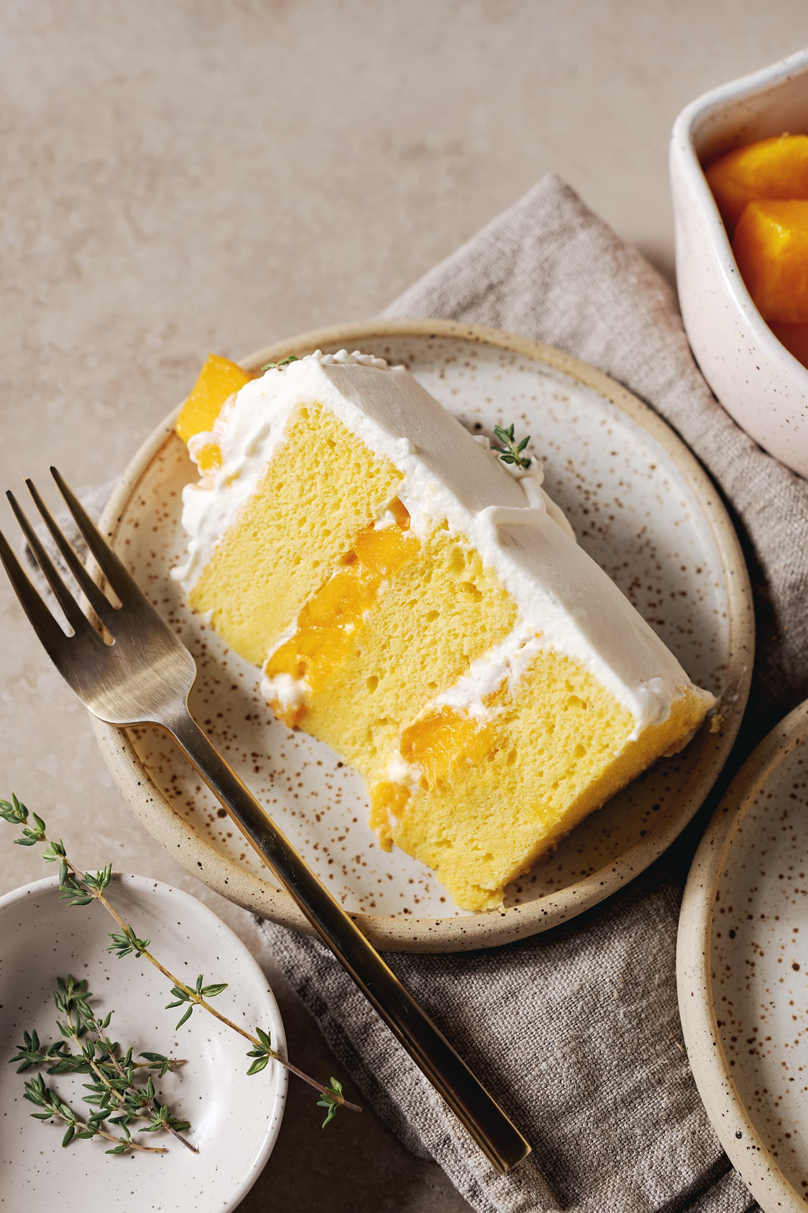 Slice of mango chiffon cake on a speckled plate with a fork.