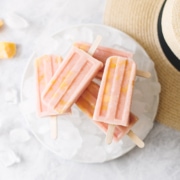 Stack of mango guava popsicles on top of plate of ice next to straw hat