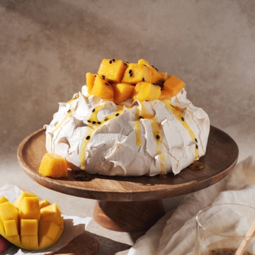 Pavlova topped with mango chunks and passionfruit puree