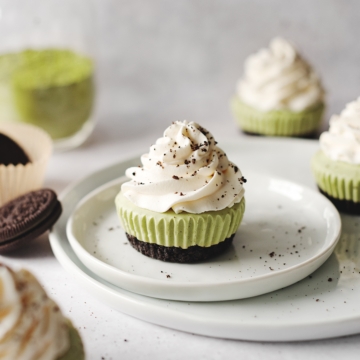 Matcha cheesecakes topped with whipped cream on plate with oreos