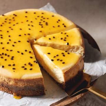 A slice of passionfruit cheesecake on a gold cake server.