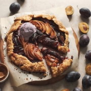 Glossy peach plum galette with a scoop of melting ice cream.