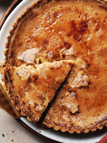 Pie server lifting a slice of pumpkin crème brûlée tart from the plate