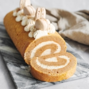 Pumpkin swiss roll with sliced piece laying in front of it