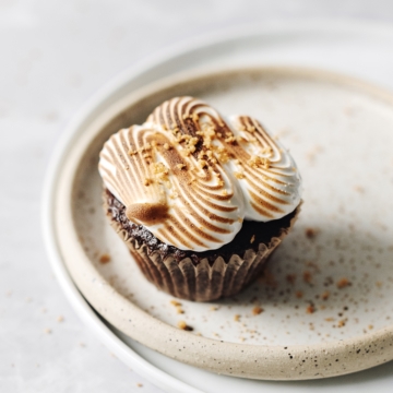 Chocolate cupcake with toasted marshmallow squiggle on top on a plate