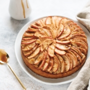 Cake with apple slices arranged on top with caramel drizzle