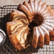 Cinnamon swirl bundt cake on wire rack with three slices cut from one side.