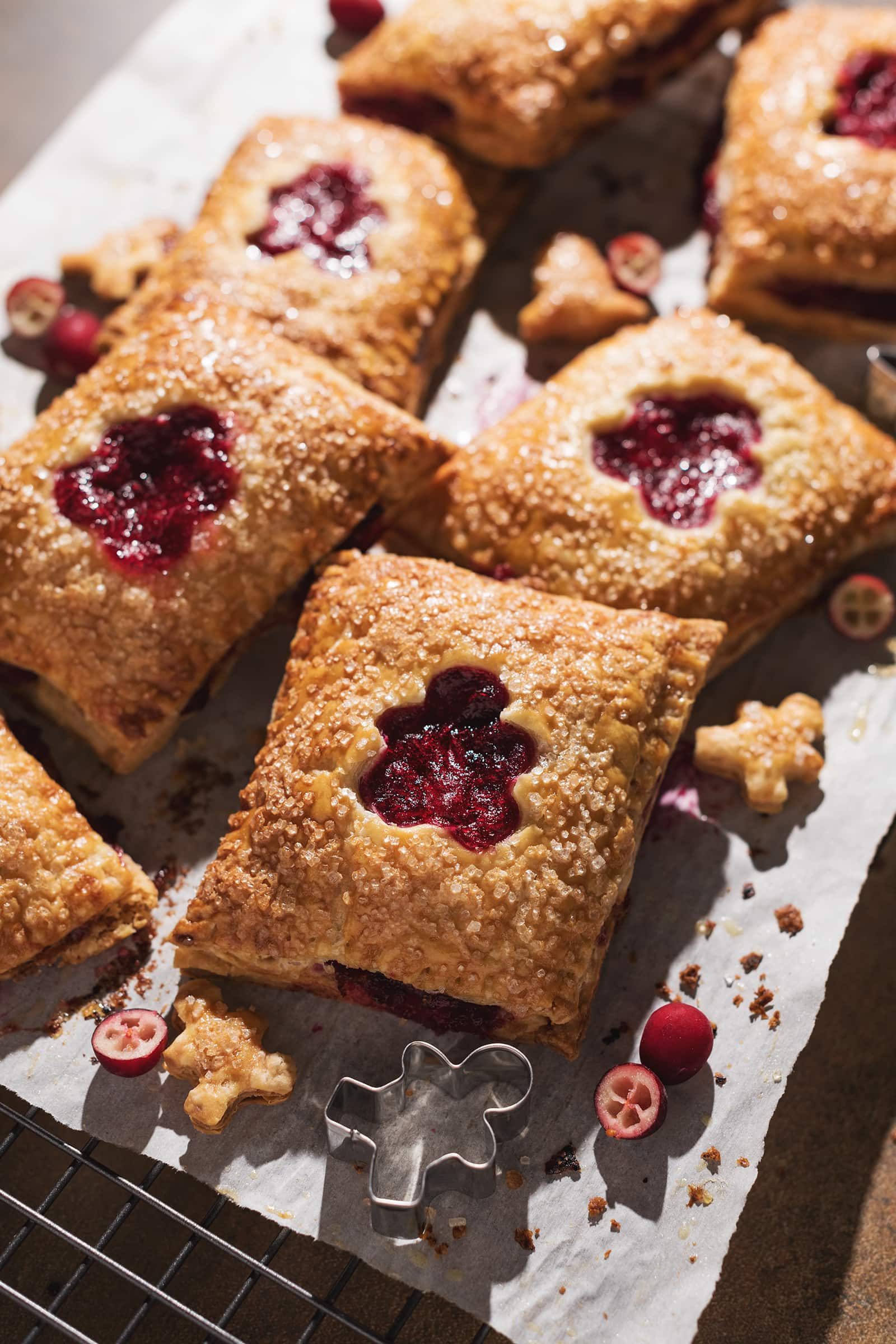 Cranberry hand pies with cutouts scattered on parchment paper.