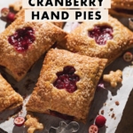 Cranberry hand pies with cutouts scattered on parchment paper.