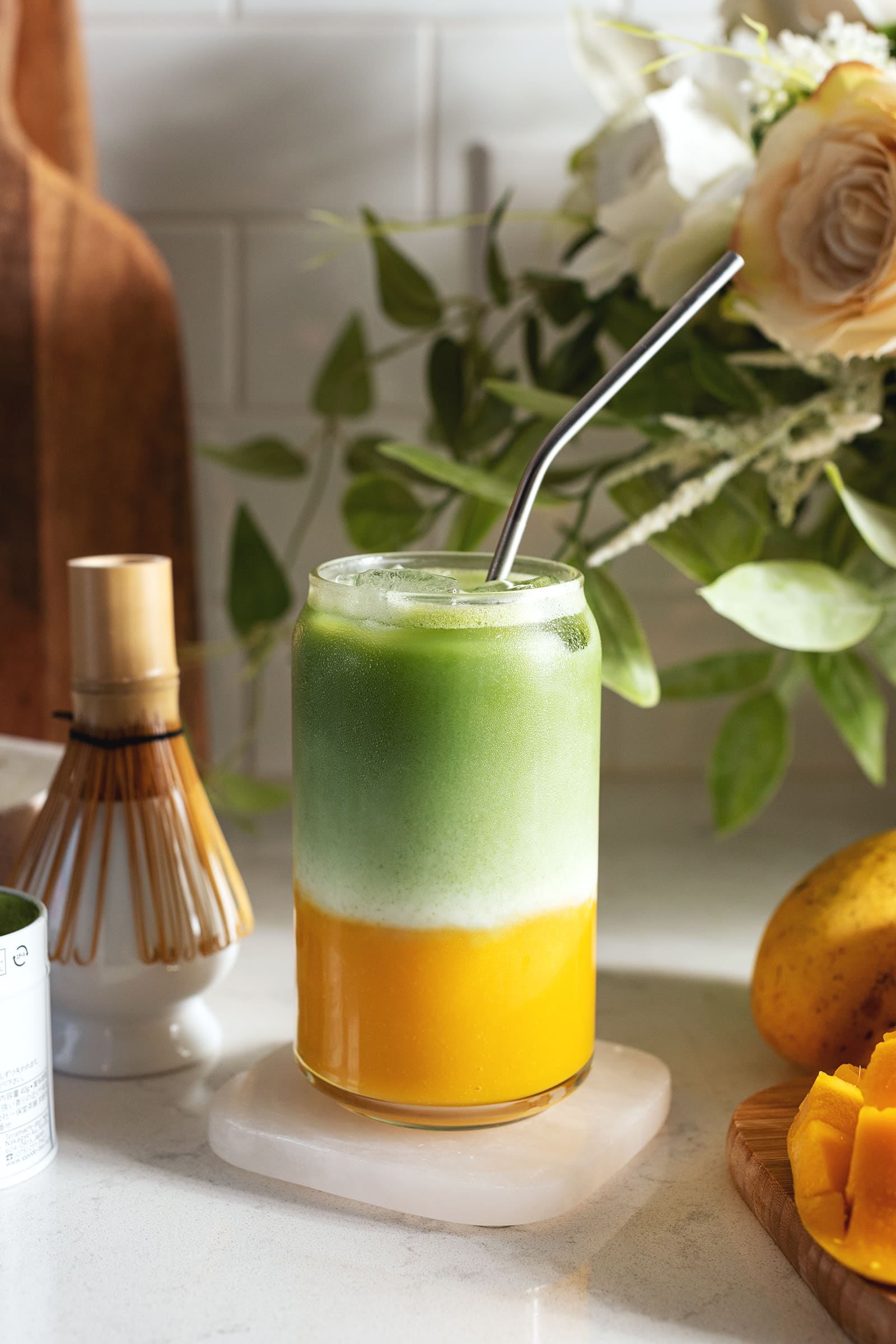 Glass filled with a layer of mango puree on the bottom and matcha on top.