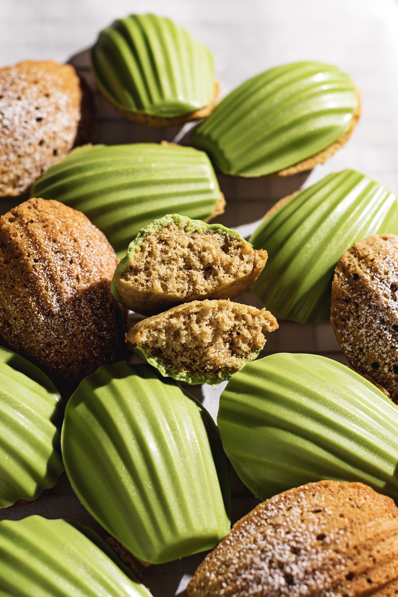 A matcha madeleine cut in half to show the fluffy texture inside.