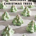 Meringue christmas trees covered in rainbow sprinkles on a baking sheet.