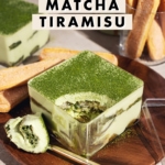 A spoonful scooped out of a box of matcha tiramisu to show the layers inside.
