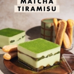 Matcha tiramisu layers in a clear box on a wooden plate.
