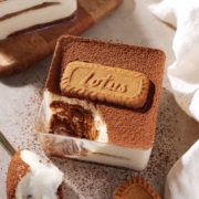 A square container of biscoff tiramisu with a spoonful scooped out of one corner.