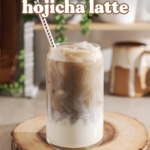 A glass filled with milk on the bottom and hojicha on top on a wood platter.