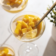 A spoonful of mango pudding resting in the glass with mango chunks on top.