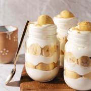 Three banana pudding jars with a spoon resting on the side.